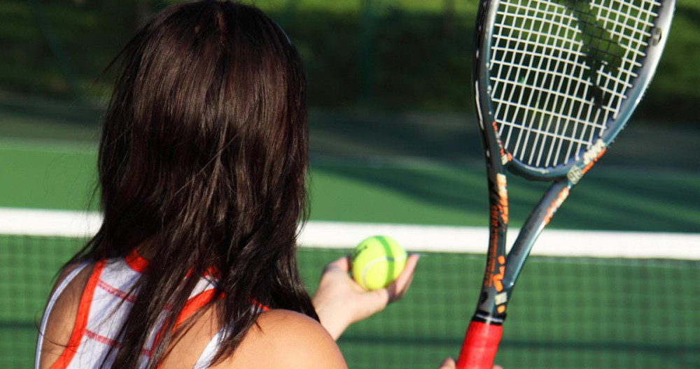 Una jugadora de tenis, de espalda, antes de un saque / Redes