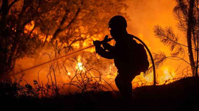 Un bombero participa anoche en la extinción de un incendio próximo al núcleo do Pereiro, en el municipio de Castrelo de Miño (Ourense), del que ha tenido que ser desalojado algún vecino por precaución ante la cercanía del fuego / EFE - BRAIS LORENZO