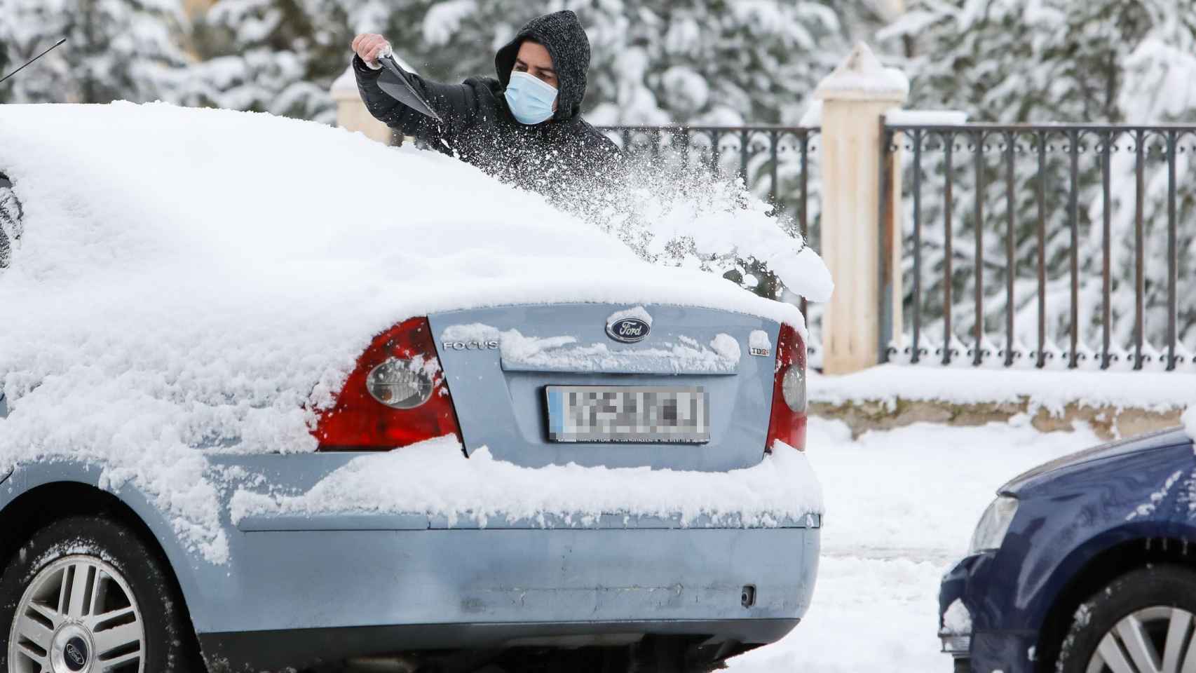 Un hombre quita la nieve de su coche ante el miedo a que se convierta en una placa de hielo por el descenso de las temperaturas / EP