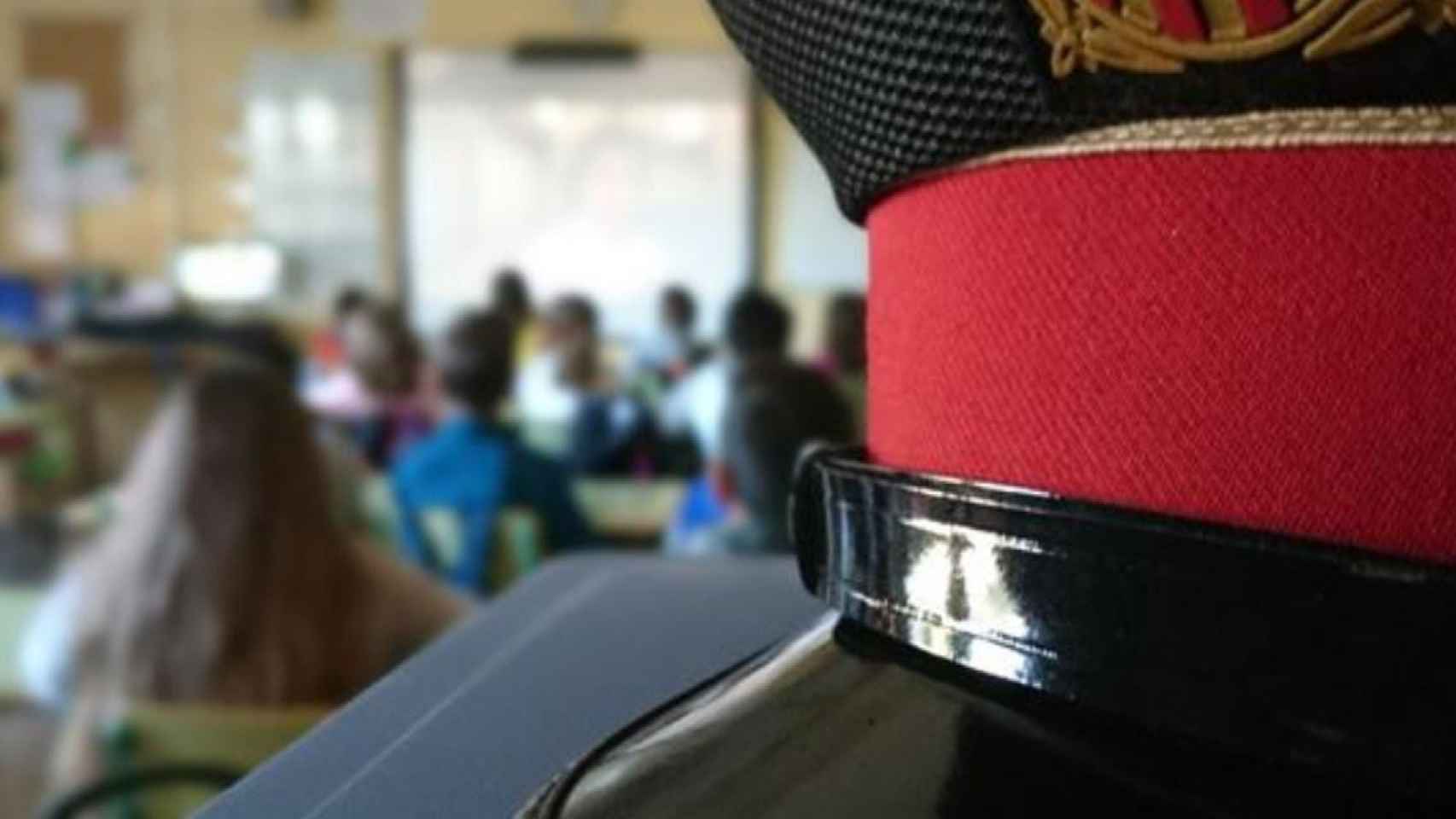 Una gorra de Mossos d'Esquadra en un aula con estudiantes para ilustrar la conciliación / MOSSOS