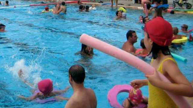 Una niña mira cómo se bañan otros niños con sus padres en una piscina / EP