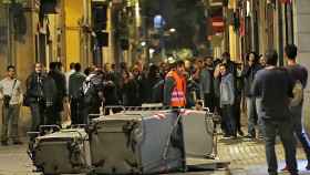 Varios manifestantes bloquean con contenedores una calle del barrio de Gracia de Barcelona en protesta por el desalojo de una antigua sucursal bancaria 'okupada'.