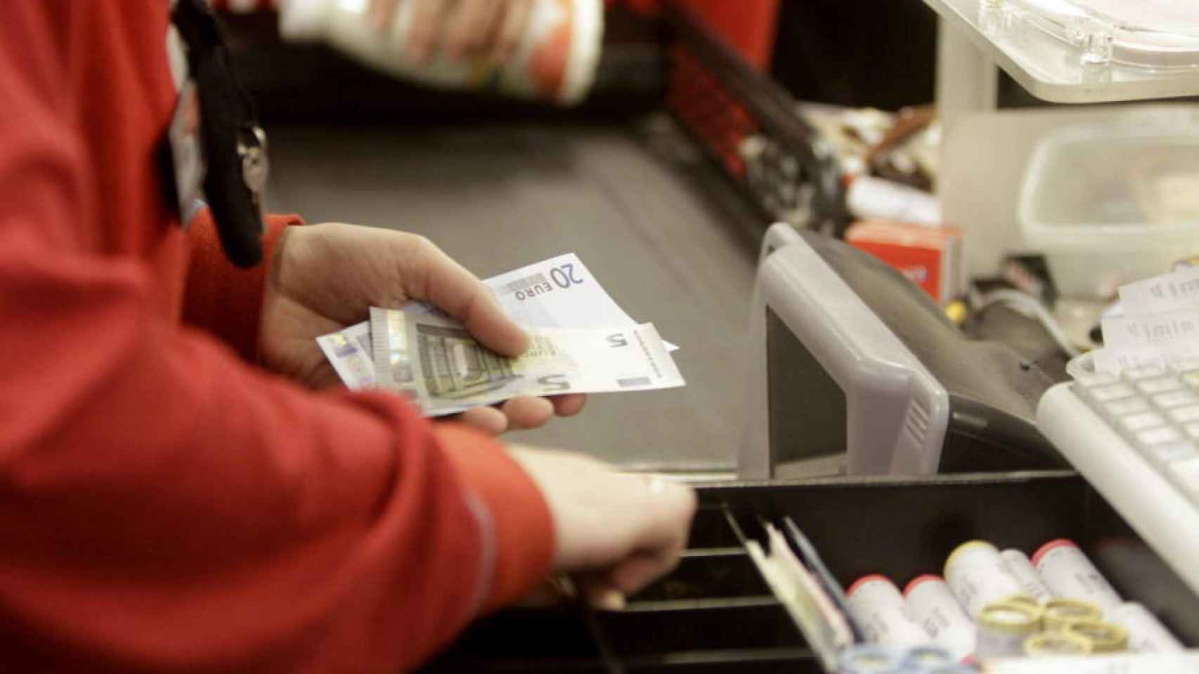 El empleado de un supermercado saca dinero de la caja registradora / EFE