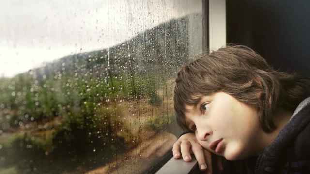 Un niño mira triste a través de una ventana / PIXABAY