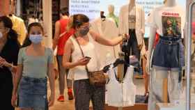 Una mujer mira ropa en una tienda con la mascarilla puesta / EUROPA PRESS
