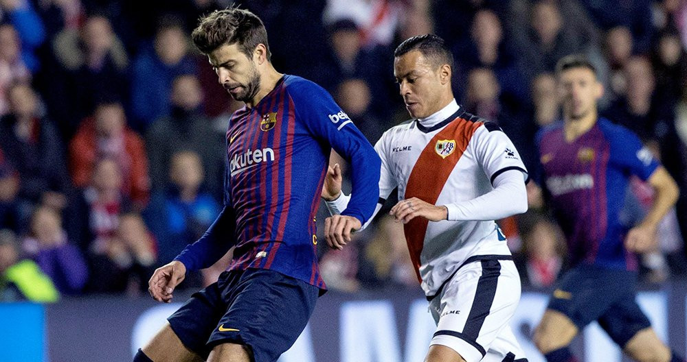 El defensa del FC Barcelona Gerard Piqué (i) juega un balón ante Raúl de Tomás, del Rayo Vallecano / EFE