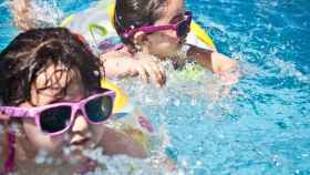 Dos niñas se bañan en una piscina municipal