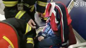 Los bomberos mientras intentan liberaral niño