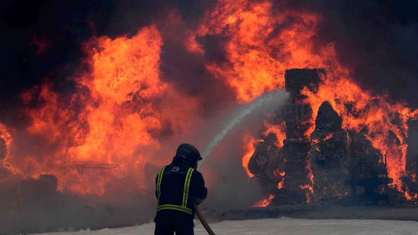 Los bomberos actuán contra el incendio en una nave de residuos de Asturias / ELOY ALONSO - EFE