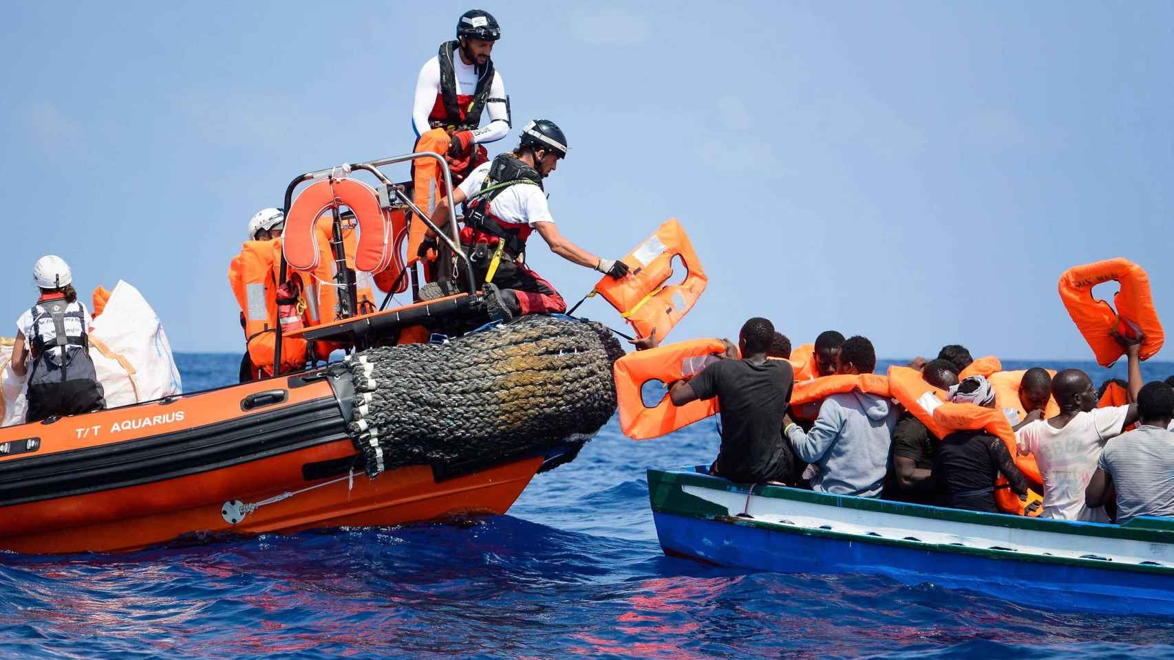 Voluntarios ayudan a los refugiados a trasladarse hacia el buque 'Aquarius' / EFE