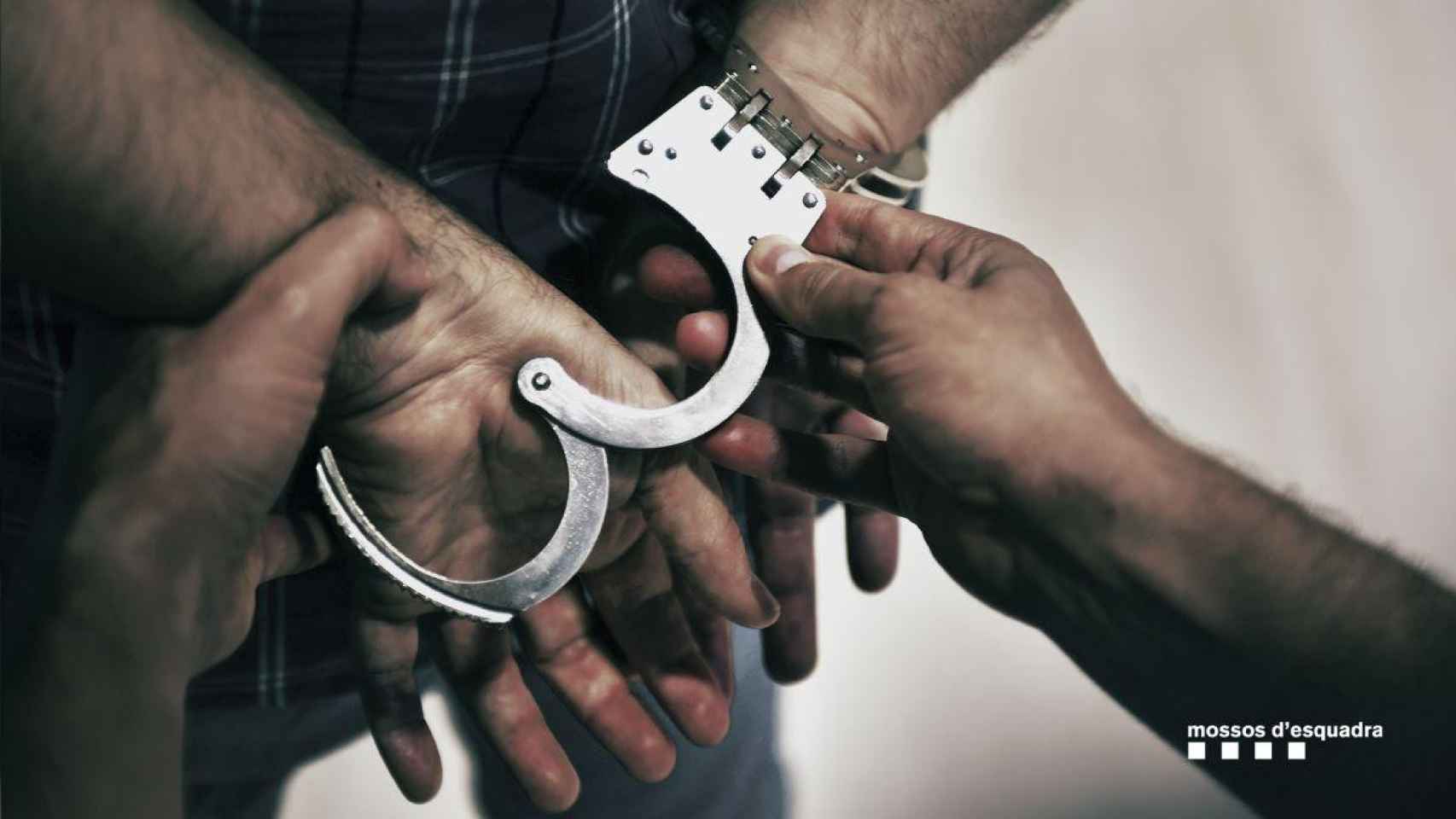 Un detenido es esposado por un agente de los Mossos / MOSSOS D'ESQUADRA