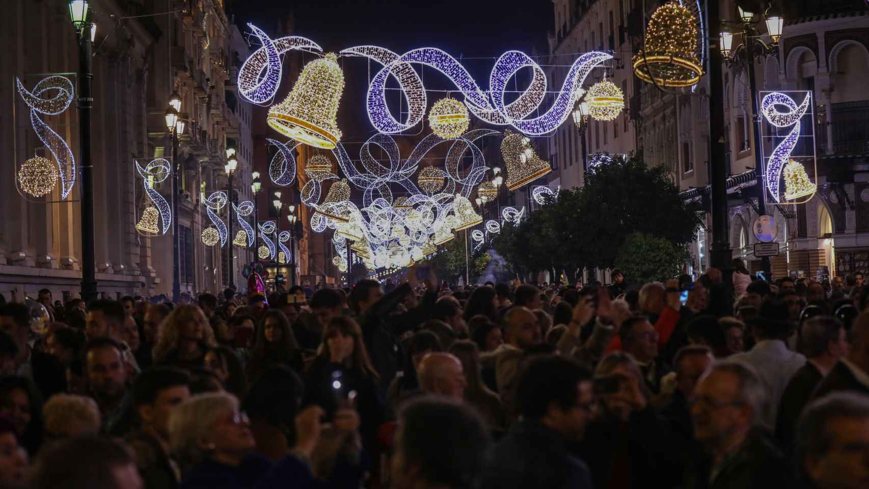 Multitud en una calle adornada con iluminación navideña / EP