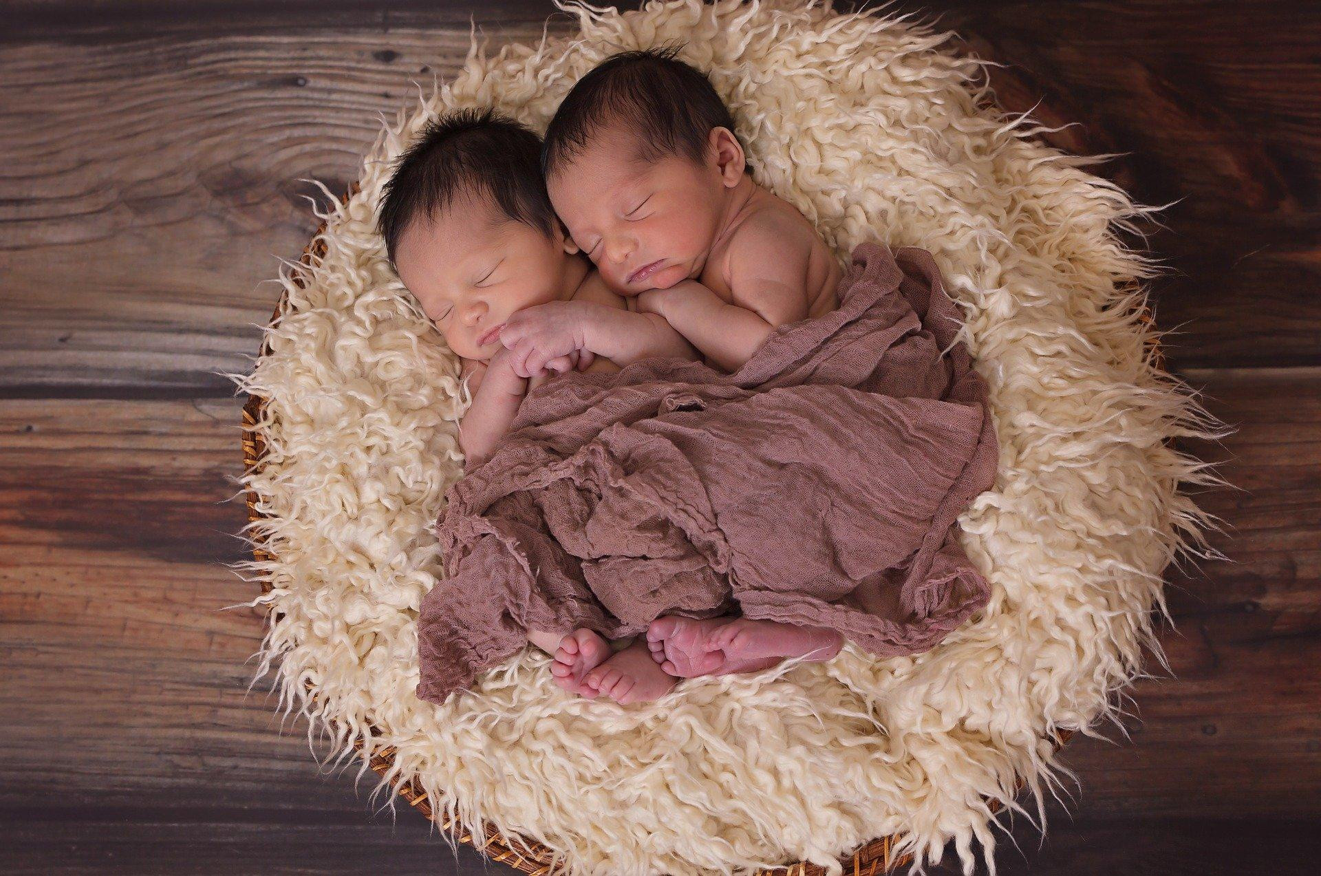 Dos gemelos posan abrazados el uno al otro mientras duermen / CG