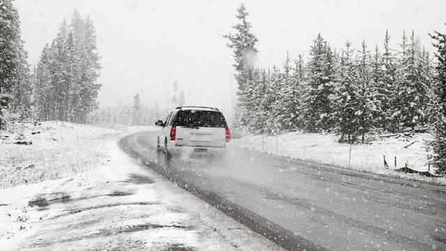 Coche circulando por una carretera cubierta de nieve / PIXNIO