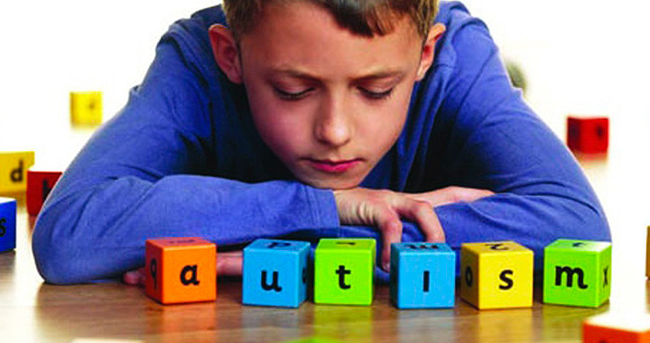 Un niño junta los cubos con la palabra autismo