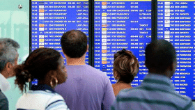 Varios pasajeros consultan la pantalla de salida de las aerolíneas el aeropuerto de El Prat de Barcelona / EFE
