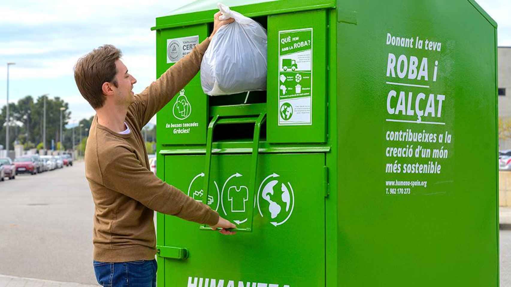 Un chico deposita ropa de segunda mano en un contenedor Humana / HUMANA