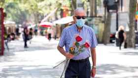 Un hombre con dos rosas y una bolsa con libros, paseando por las Ramblas de Barcelona en el Sant Jordi veraniego / EFE