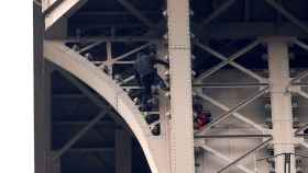 Un hombre escala la Torre Eiffel mientras varios bomberos tratan de detenerlo / EFE