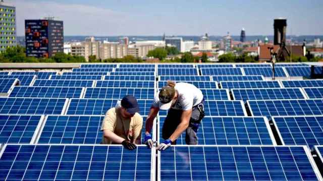 Dos operarios instalan las placas de una instalación fotovoltaica de autoconsumo, el nuevo negocio de Siroco Capital. Imagen del artículo 'No nos mires, ponte placas' / EFE