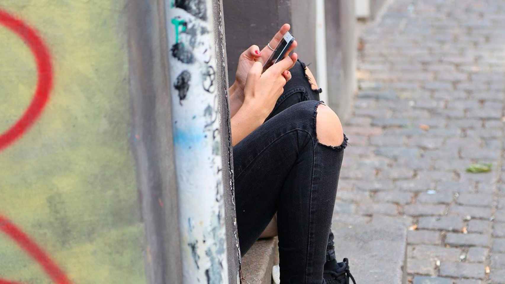 Una chica manda mensajes desde su móvil escondida / FREEPIK