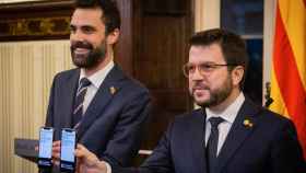 El presidente de la Generalitat, Pere Aragonès (d), y el consejero catalán de Empresa y Trabajo, Roger Torrent (i), muestran sus móviles / EUROPA PRESS
