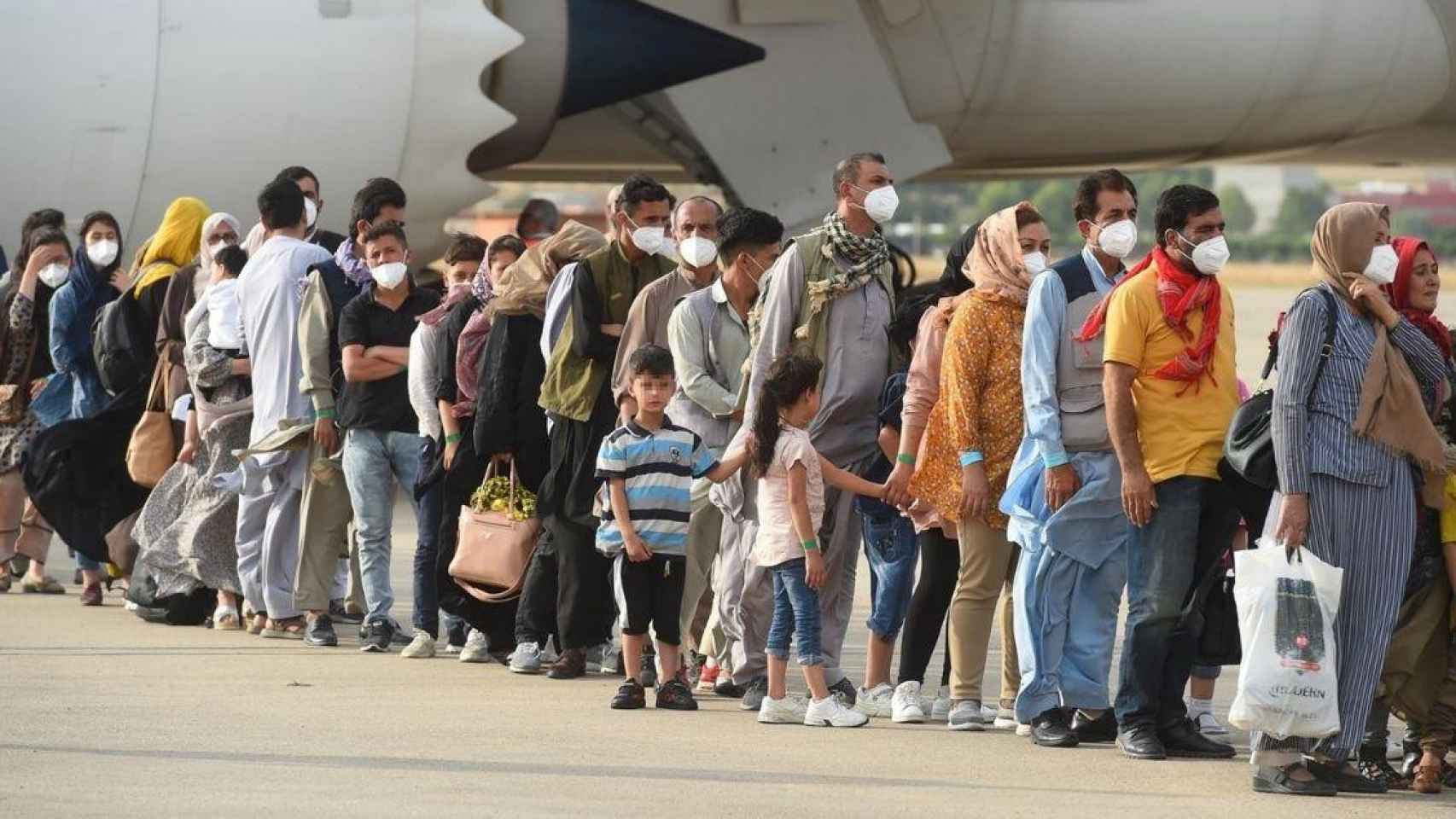 Algunos de los 260 afganos que han llegado este lunes en un avión a la base aérea de Torrejón de Ardoz (Madrid) / Fernando Villar (EFE)