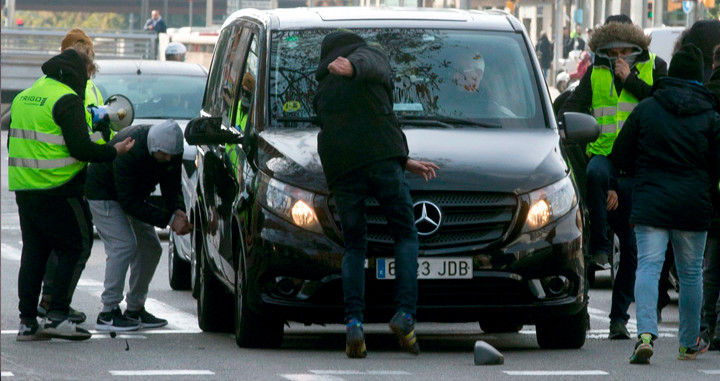 Taxistas de Barcelona atacando un vehículo VTC, como los que utilizan Uber y Cabify, ayer / EFE