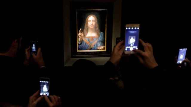 Varias personas fotografían la obra 'Salvator Mundi' del artista Leonardo da Vinci