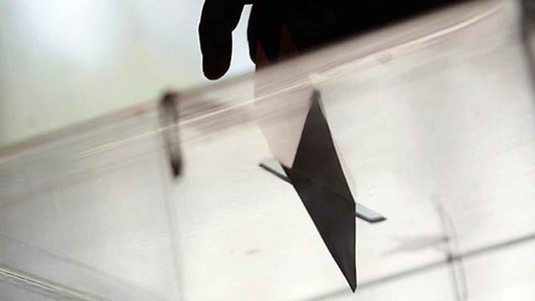 Un hombre inserta un sobre en una urna en las elecciones en una mesa electoral / EFE