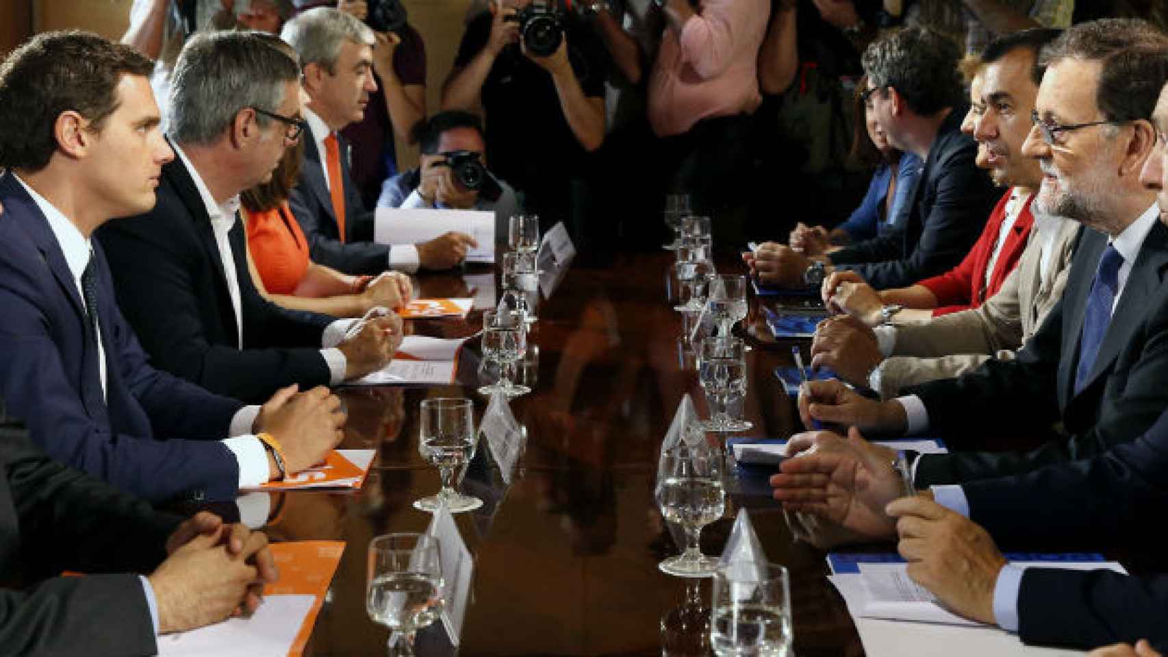 Los equipos negociadores de PP y Ciudadanos, liderados por Rivera y Rajoy, este domingo antes de firmar el acuerdo de investidura. / EFE