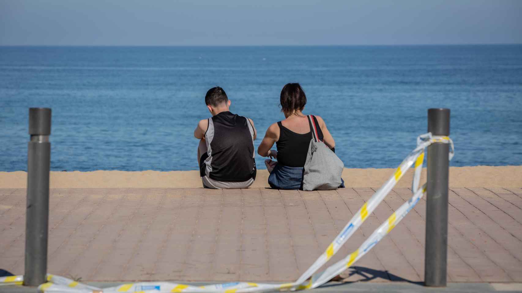 Dos personas sentadas frente a la playa de la Barceloneta / EP