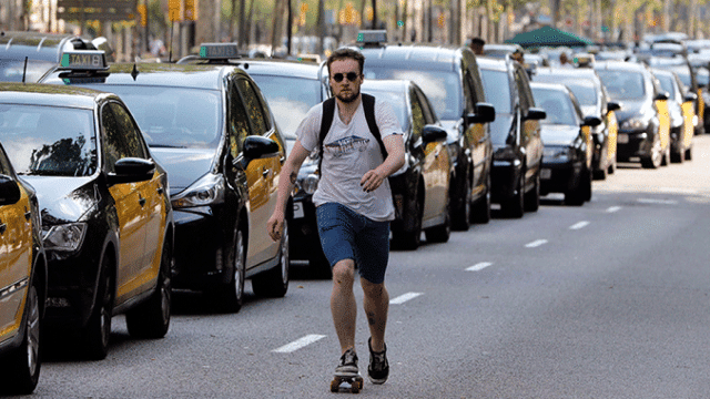 Un joven pasa por delante de los taxis que ocupan la Gran Via de Barcelona / EFE