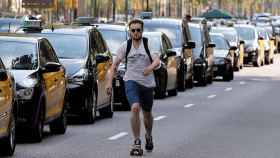 Un joven pasa por delante de los taxis que ocupan la Gran Via de Barcelona / EFE