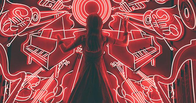 Una mujer se sitúa frente a un mural luminoso de música / UNSPLASH
