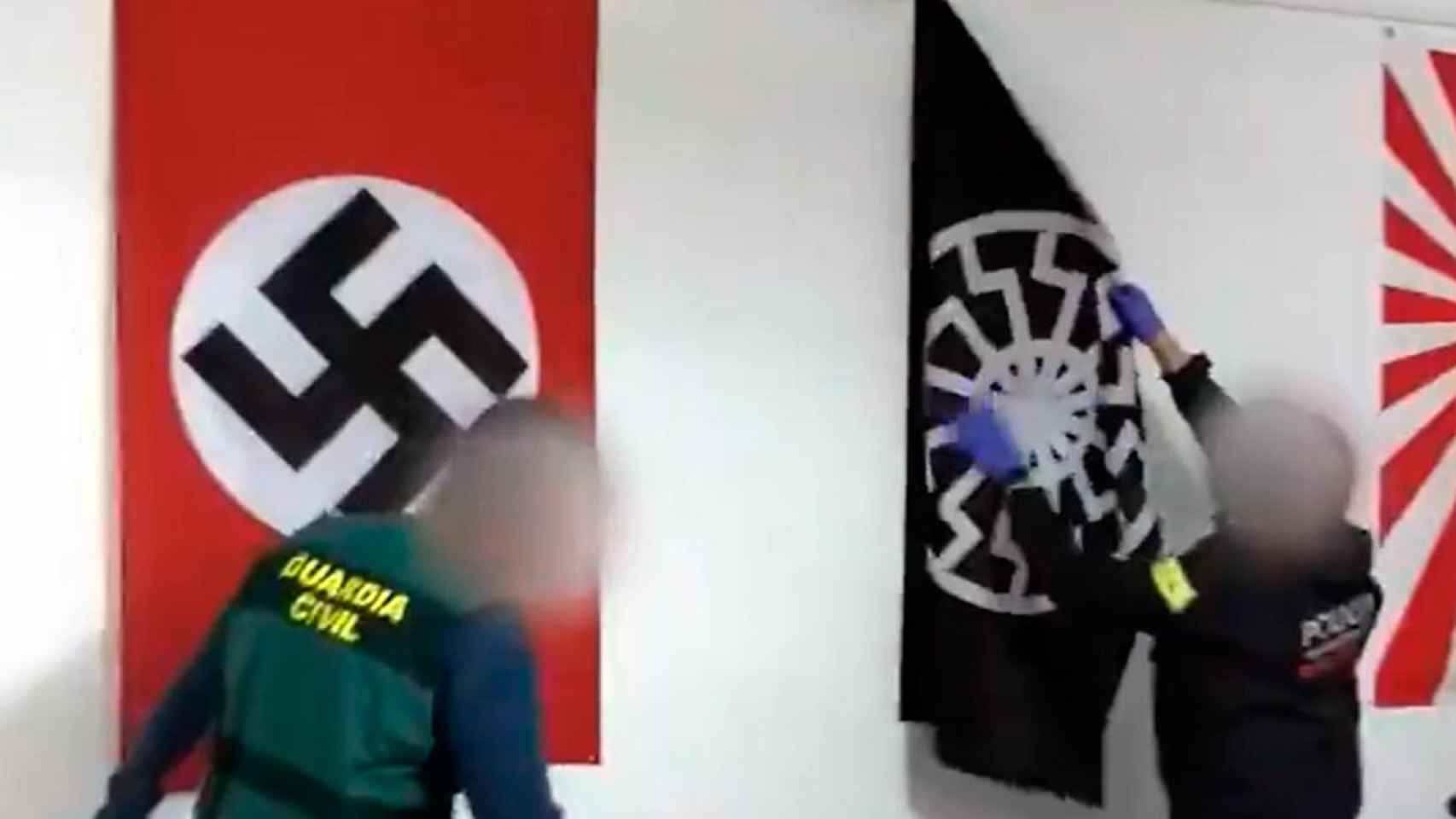 Un mosso y un guardia civil retiran simbología nacionalsocialista de casa de uno de los arrestados por supremacismo blanco / MOSSOS