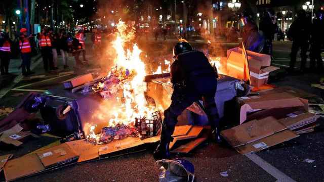 Imagen de un mosso d'esquadra tratando de apagando una barricada en Barcelona / EFE