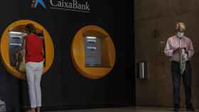 Dos personas sacan dinero de un cajero de Caixabank / EUROPA PRESS