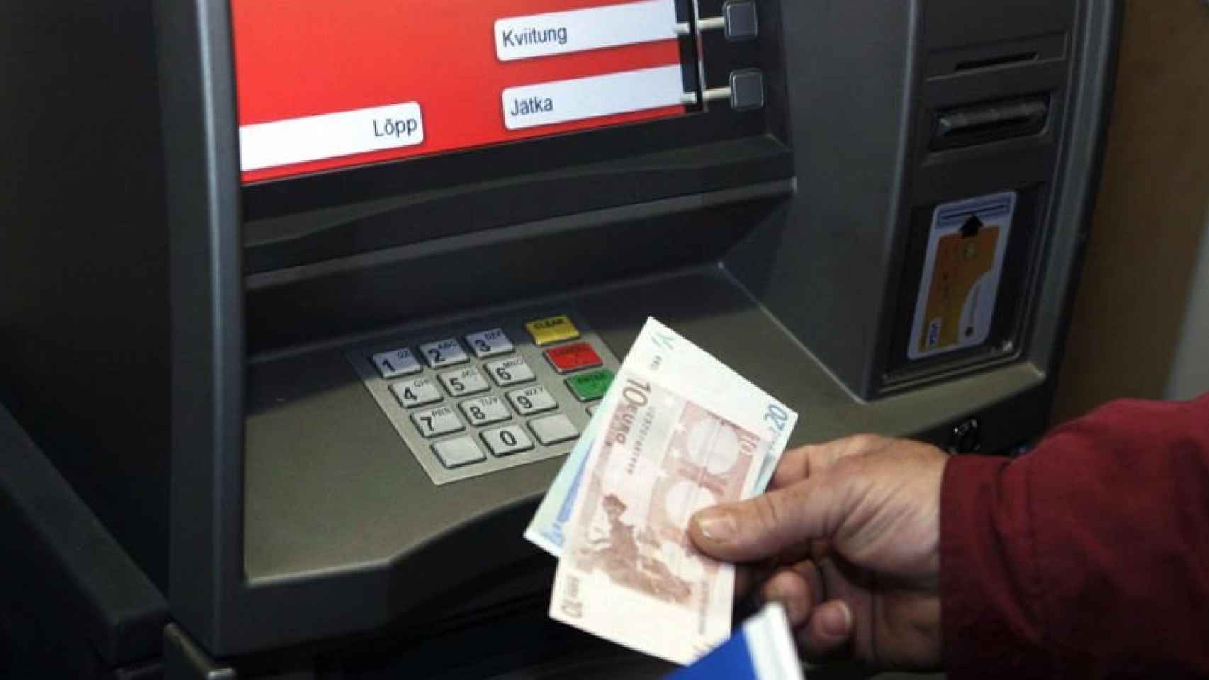 Un hombre saca dinero de un cajero automático sin comisiones en el extranjero en una imagen de archivo / CG
