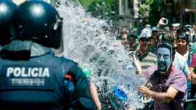 Uno de los okupas del Banc Expropiat de Gràcia lanza un cubo de agua a una de sus víctimas, un agente de los Mossos. La asociación de víctimas de okupas llega a Cataluña / EFE
