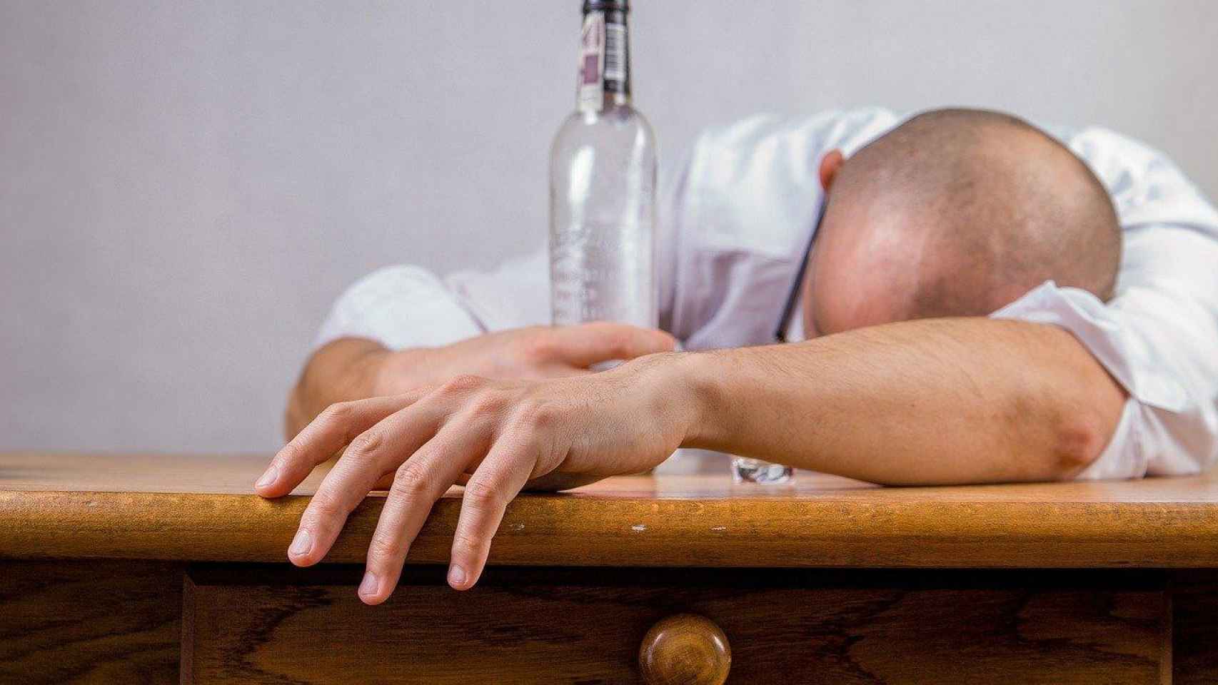 Un hombre junto a una botella de alcohol vacía, para ilustrar la adicción / PIXABAY