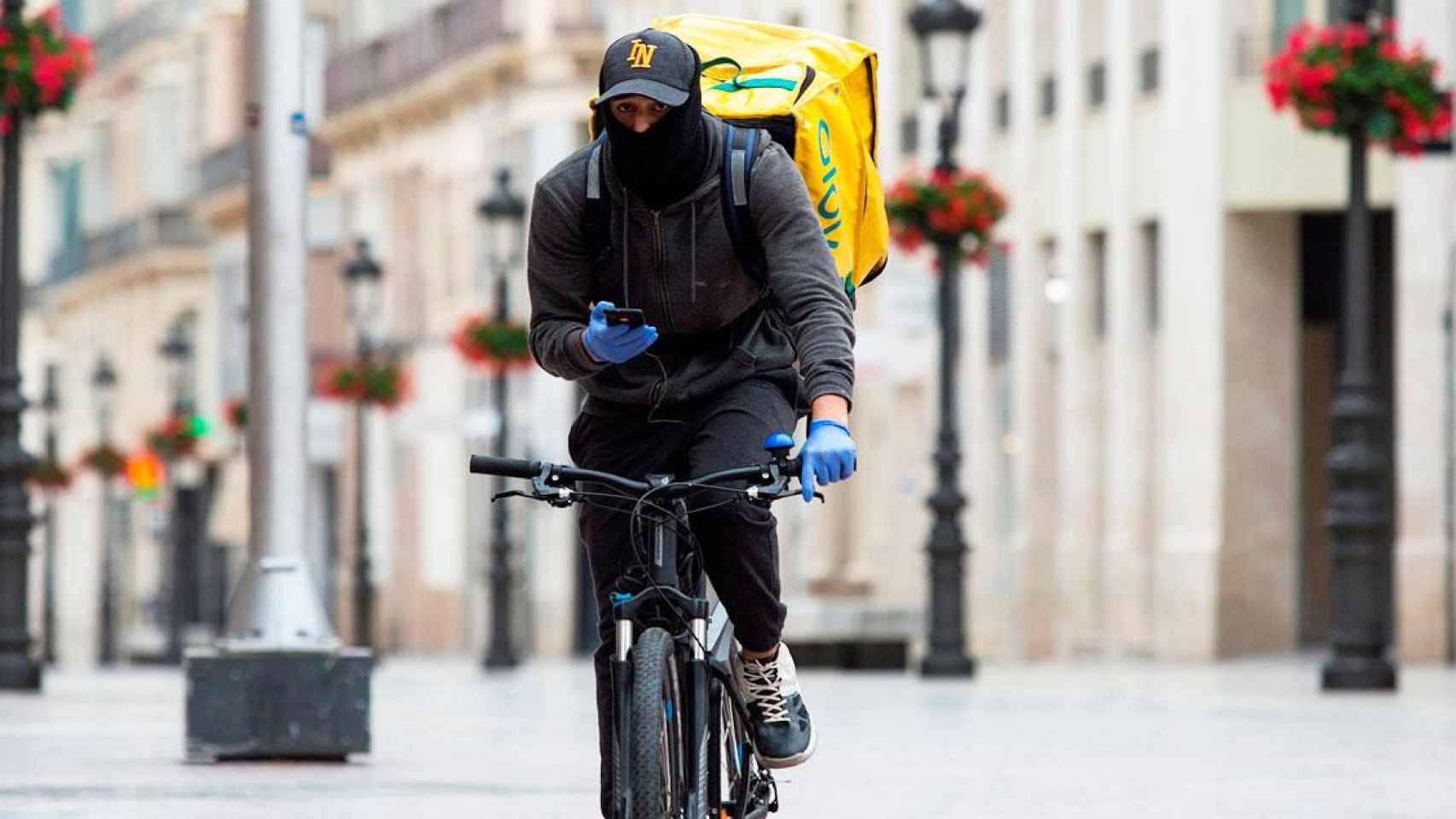 Imagen de un 'rider' de Glovo circulando por el centro de Barcelona en plena reclusión / EFE