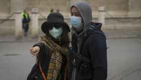 Dos turistas pasean por Sevilla protegidos del coronavirus por una mascarilla / EP