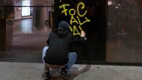 Imagen de un manifestante pintando una entidad bancaria / EP