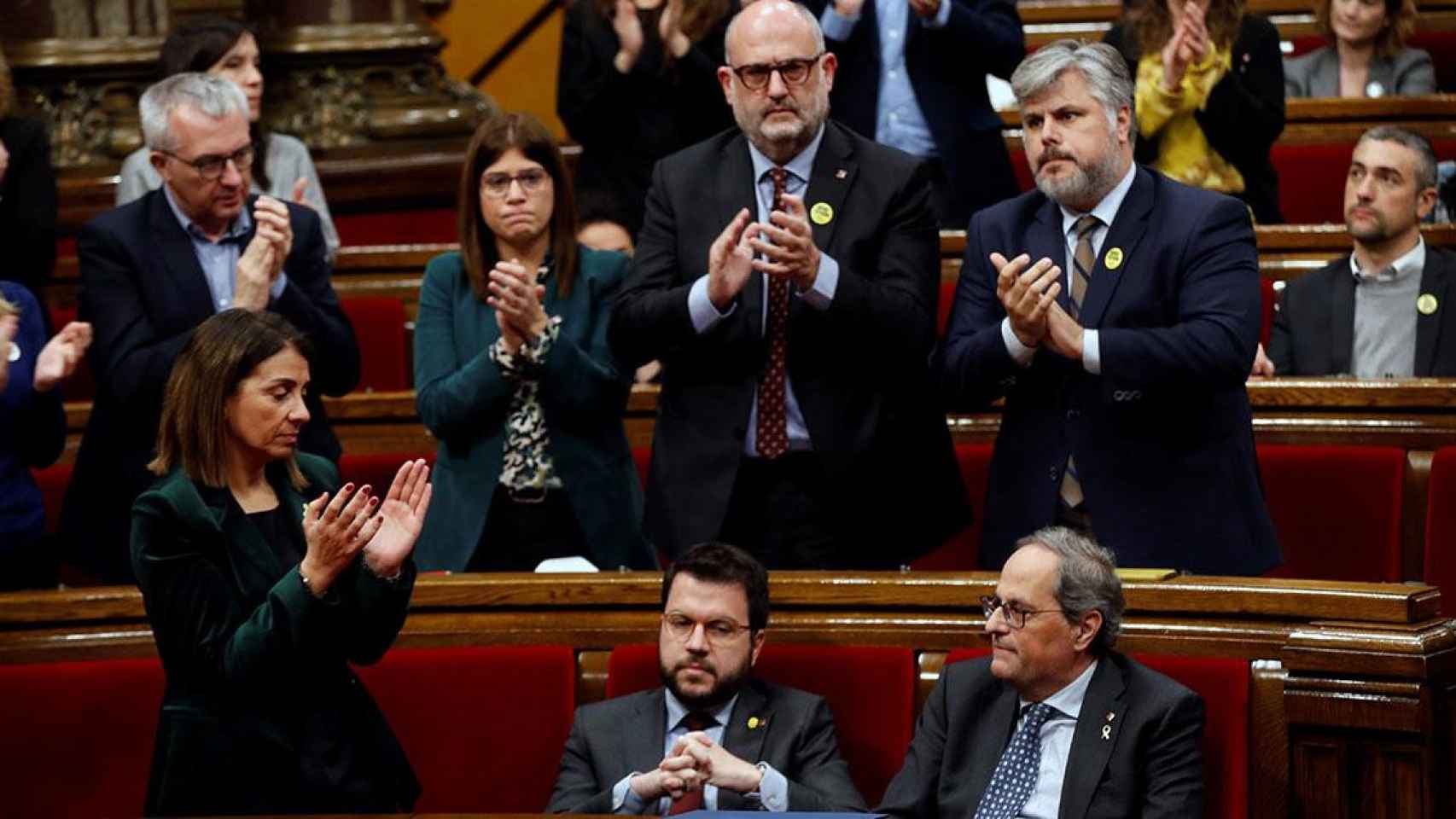 El presidente de la Generalitat, Quim Torra (d), es aplaudido por los miembros de su partido mientras que su vicepresidente, Pere Aragonés (i), y los diputados de ERC permanecen sentados / EFE