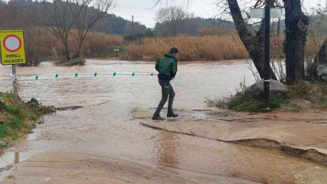 Un agente de Agents Rurals ante un río inundado / Protecció Civil