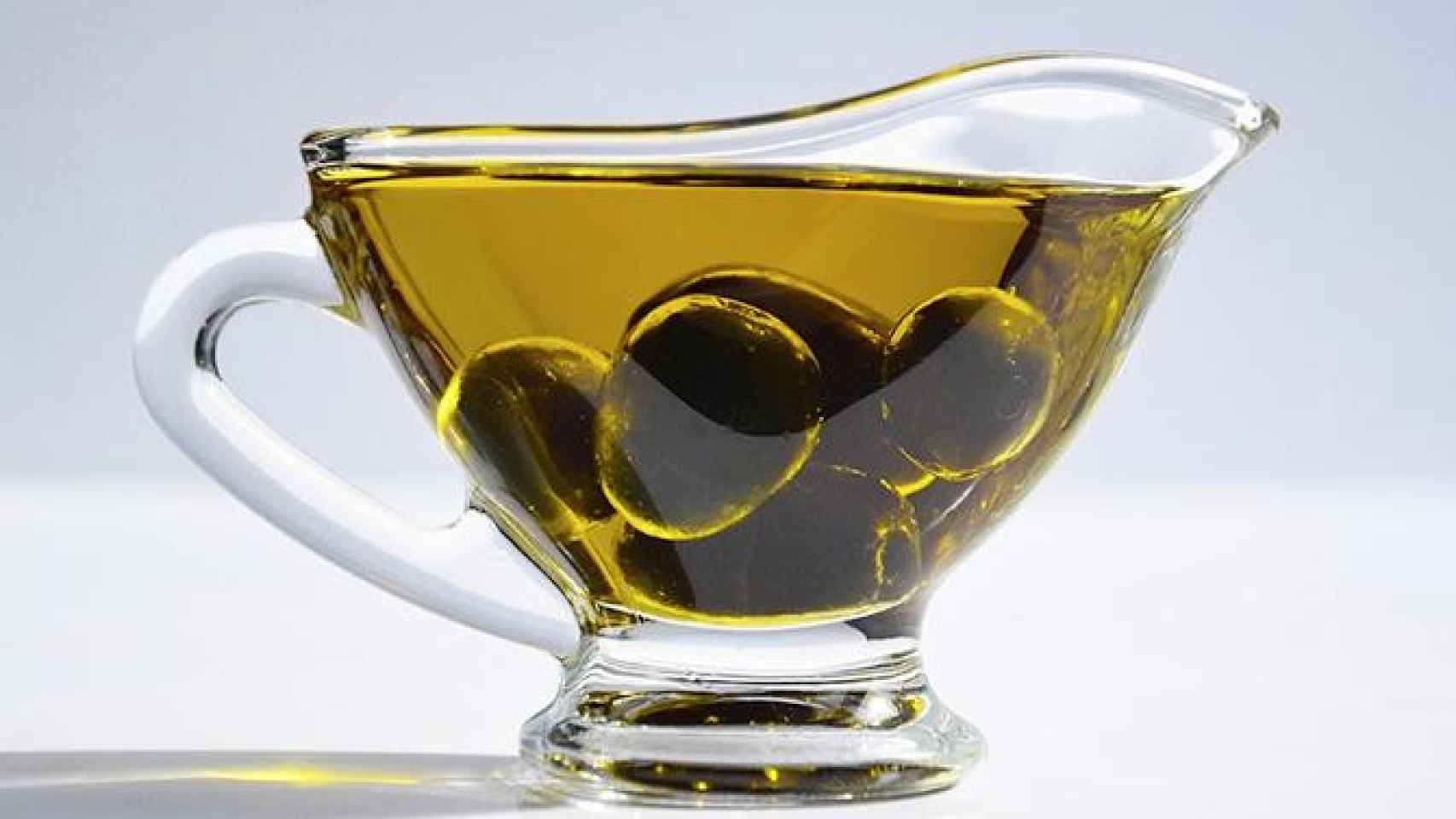 Una taza con aceite de oliva y unas aceitunas