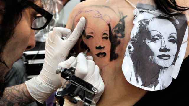 Un especialista plasmando un tatuaje sobre el cuerpo de una joven / CG