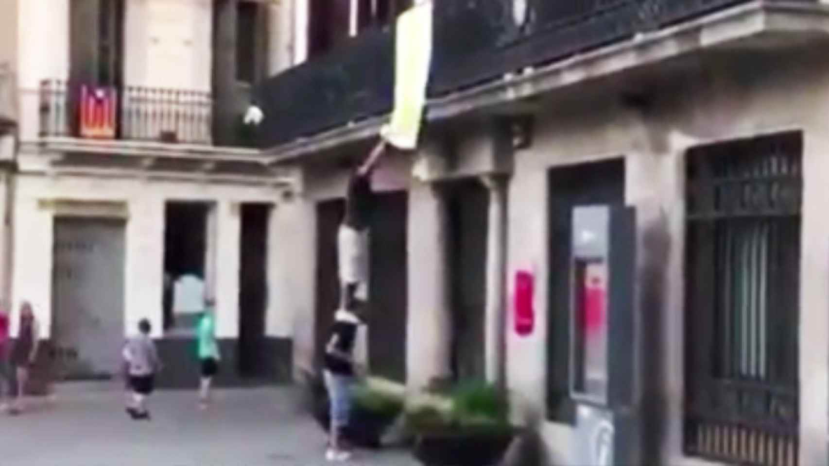 Dos personas arrancando el lazo amarillo de la sede del distrito de Sant Andreu de Barcelona ayer / CG