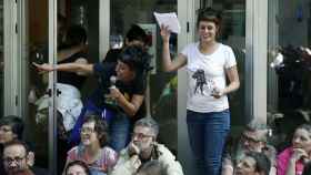 Anna Gabriel, con el micrófono en la mano, señala a los policías desde la puerta de la sede de la CUP. A su lado, con camiseta blanca, Mireia Vehí / EFE